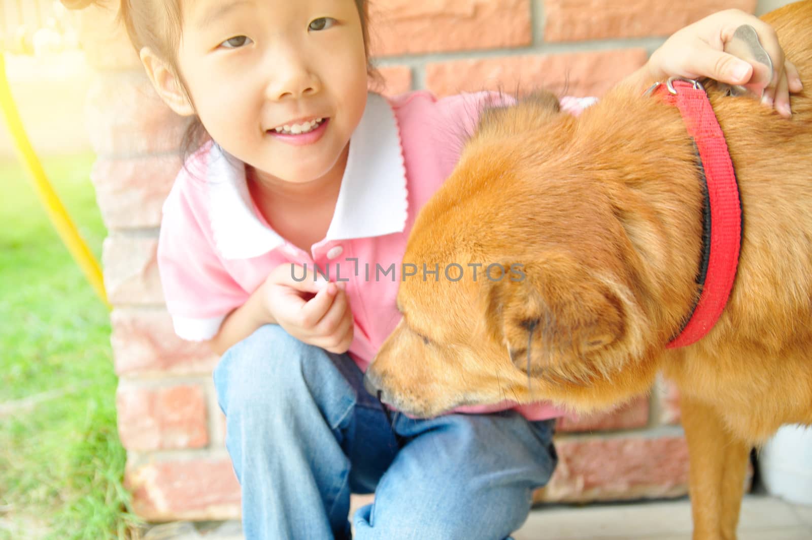 little girl is hugging dog outdoors