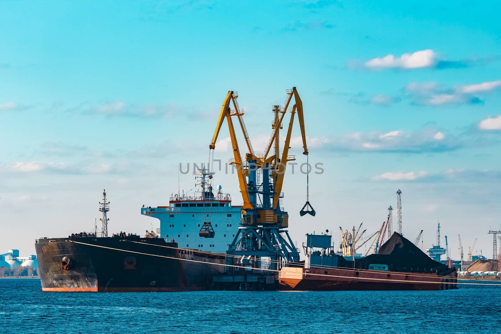 Black cargo ship loading with a coal at the port