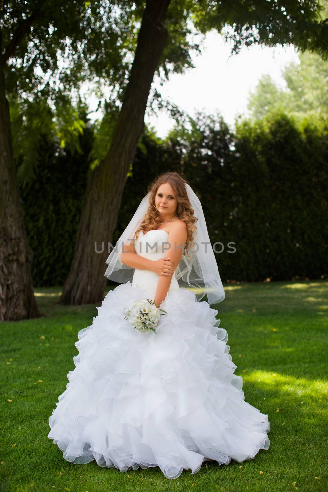 Stylish bride in a white dress in the countryside