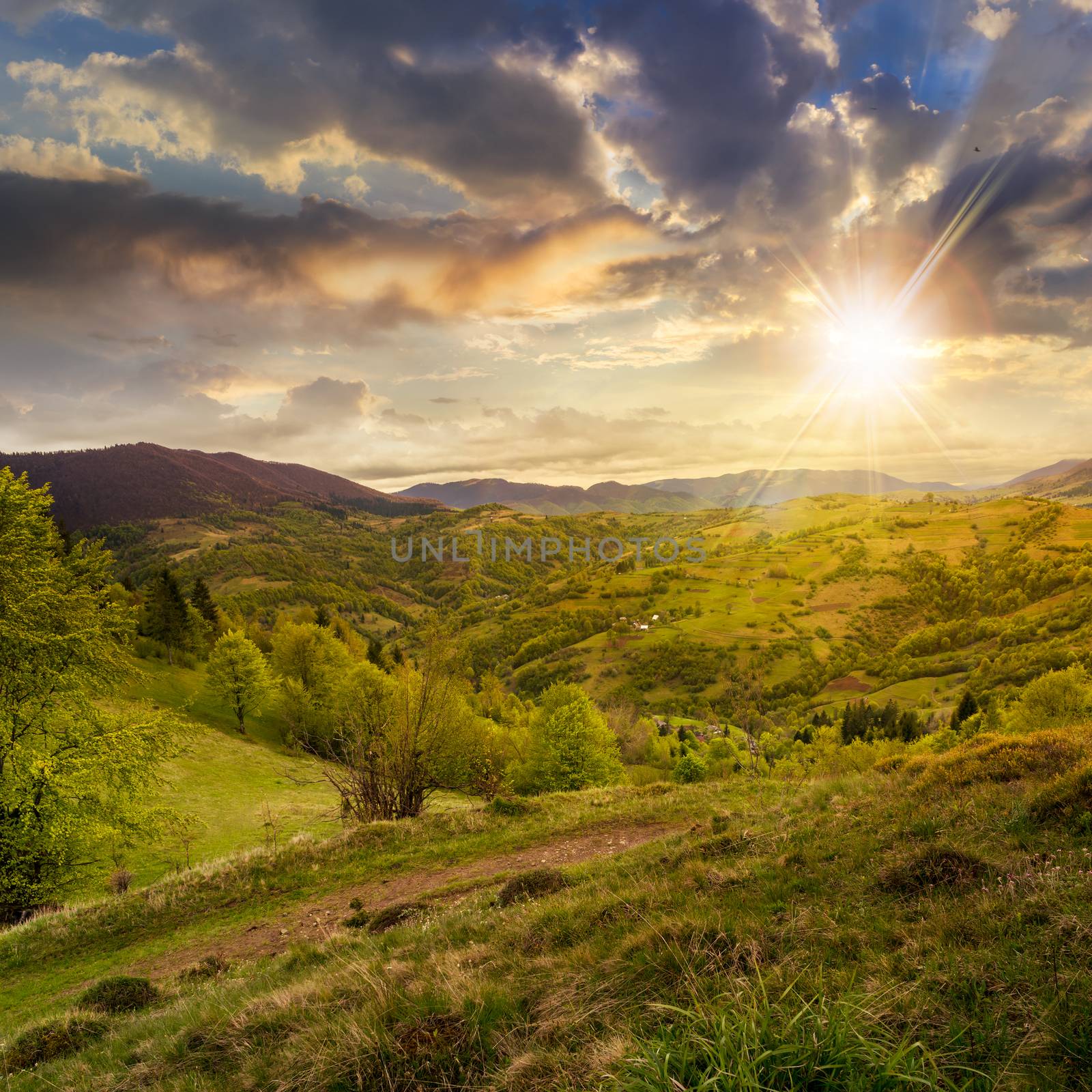 green fields in the mountains near native village under a blue summer sky at sunset