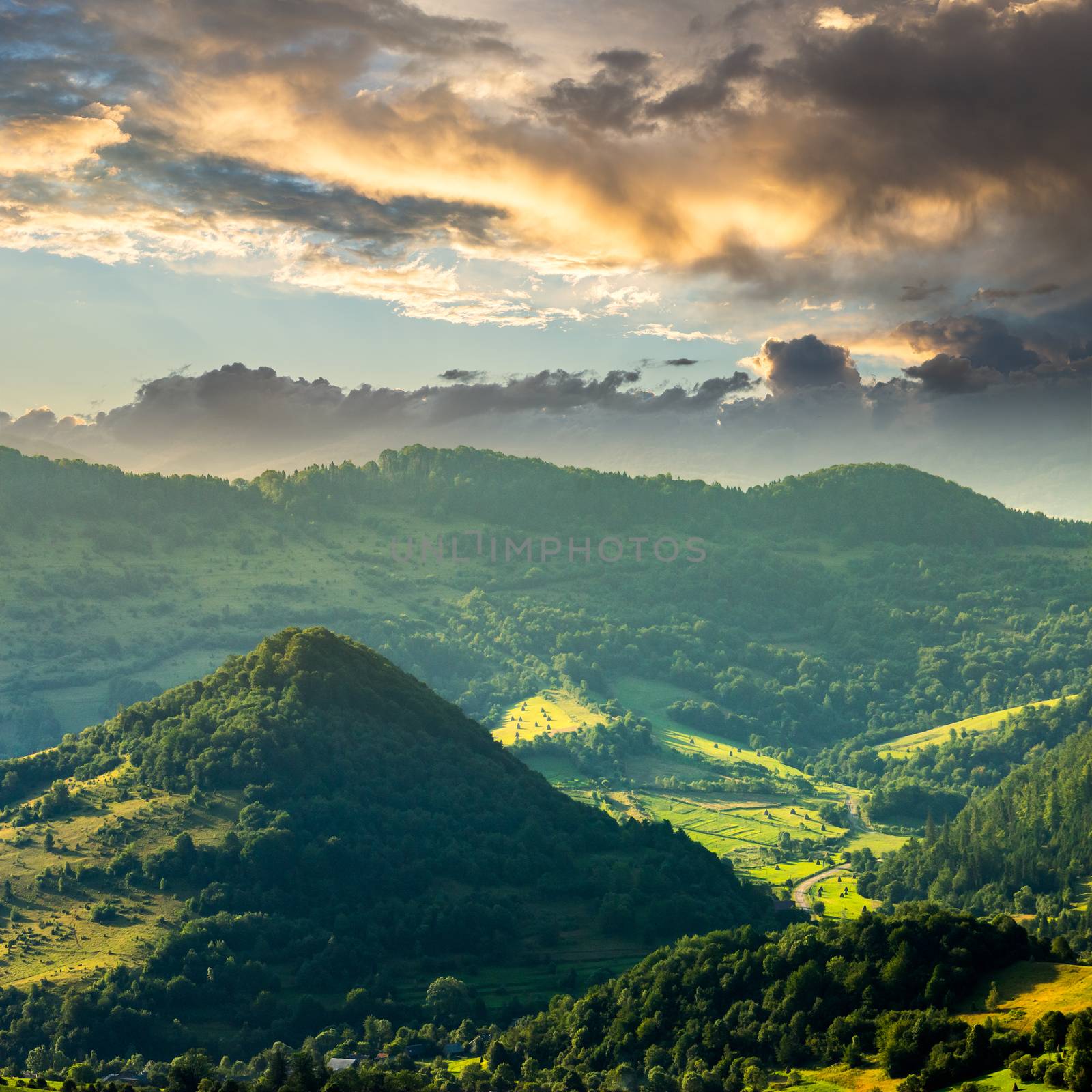 slope of mountain range with coniferous forest and village at sunrise
