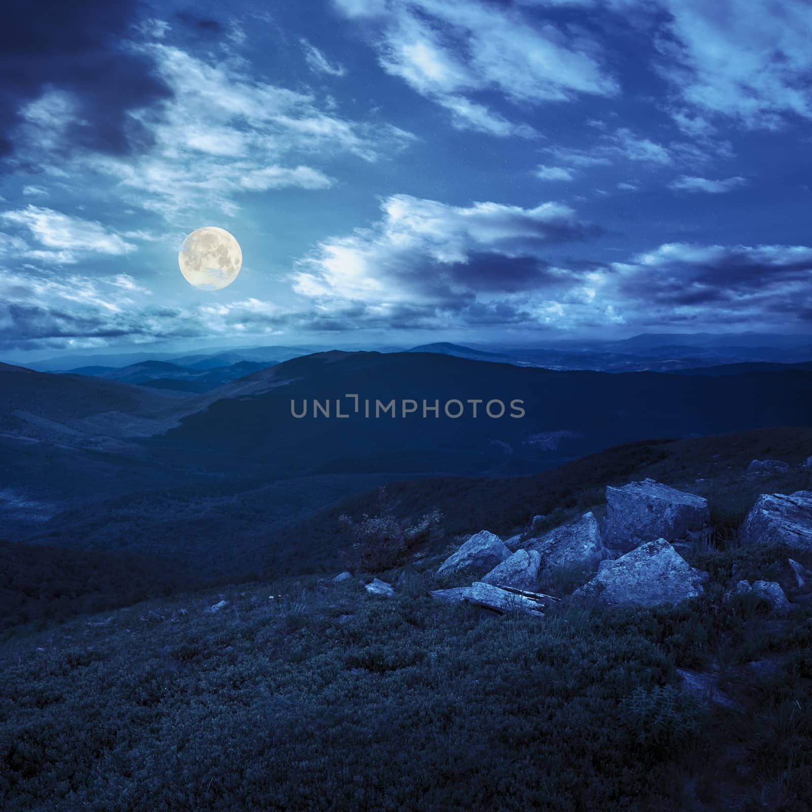 white sharp stones on the hillside of high mountains at night in full moon light