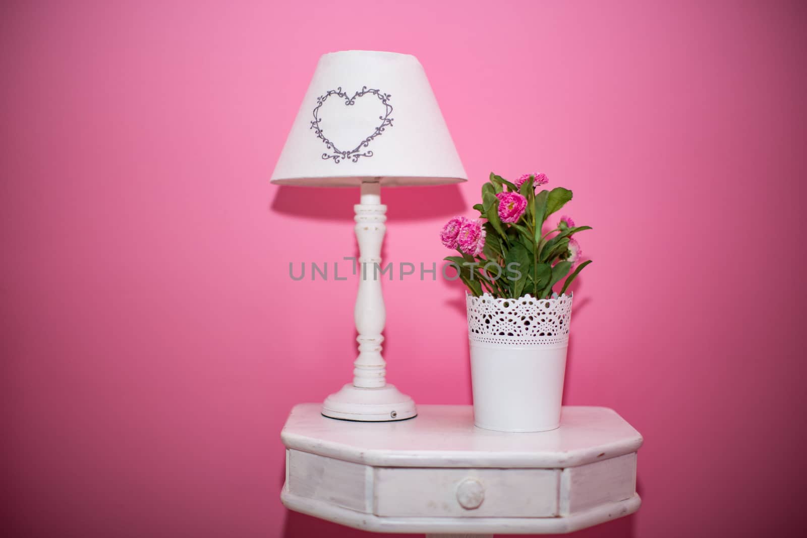 Table lamp and bouquet of flowers on a pink background. by boys1983@mail.ru