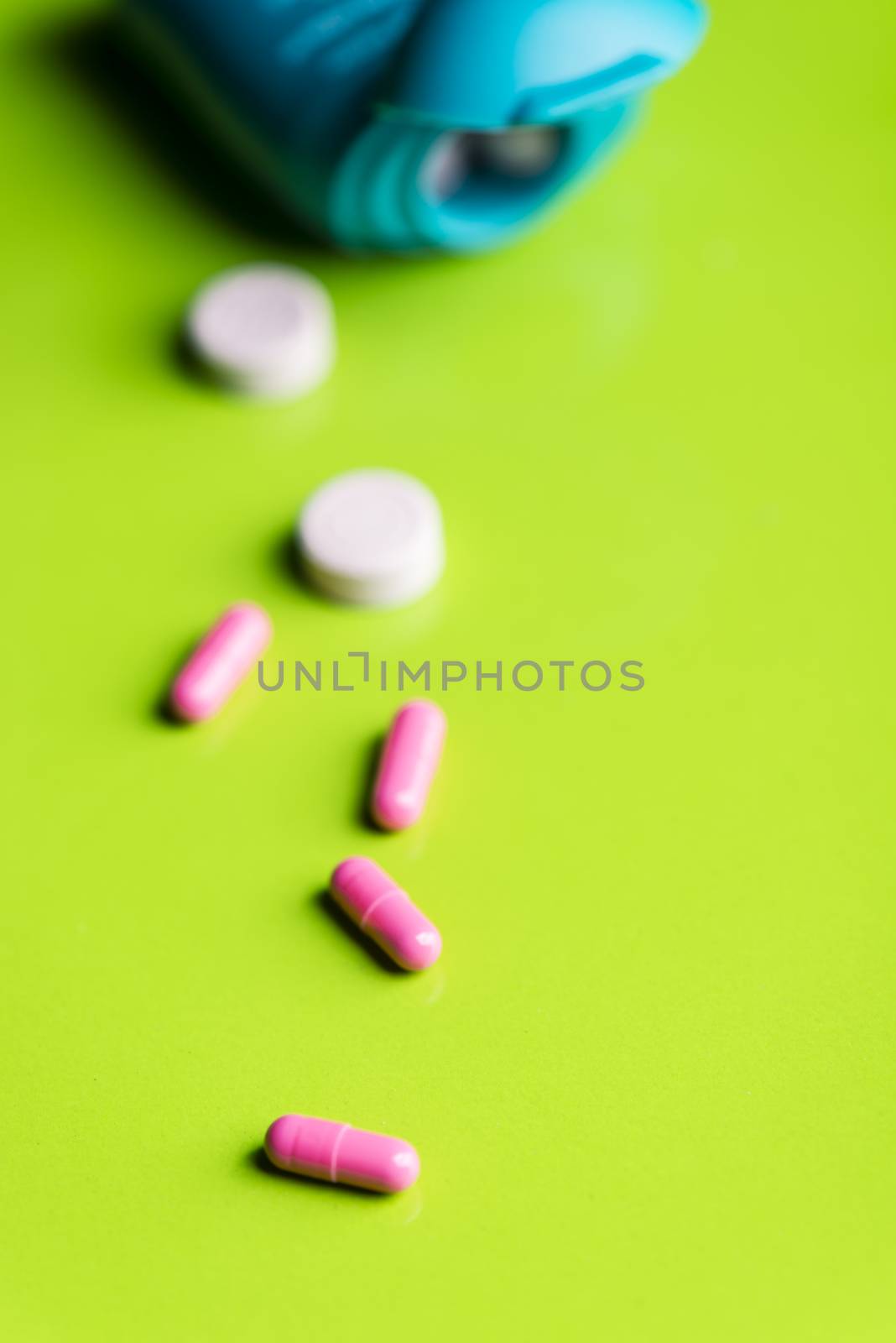 pink pills and medicine over a green table and backrgound