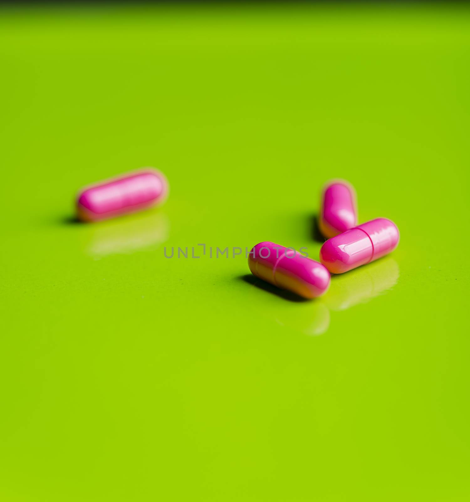 pink pills and medicine over a green table and backrgound