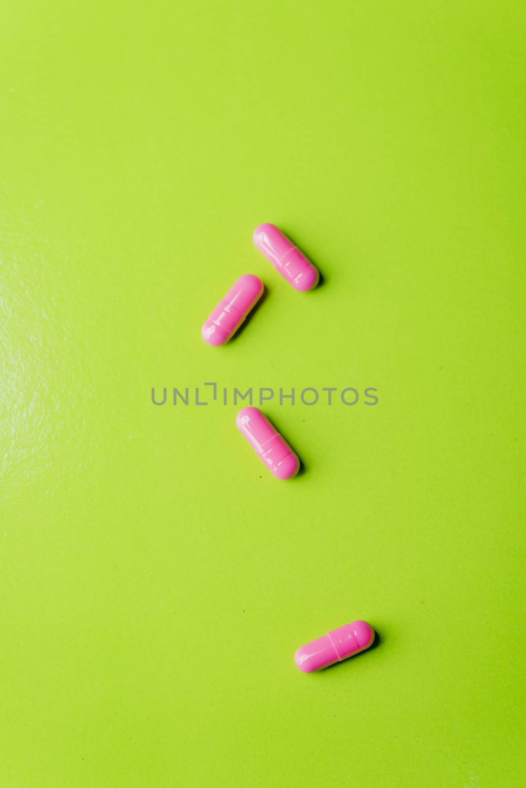 pink pills and medicine over a green table and backrgound