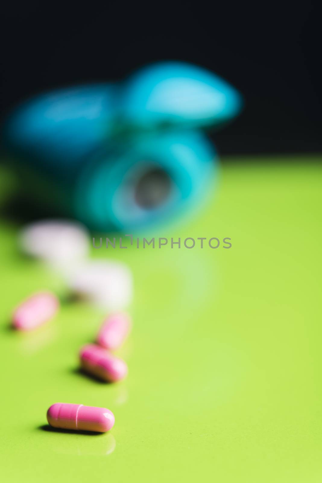 pink pills and medicine over a green table and backrgound