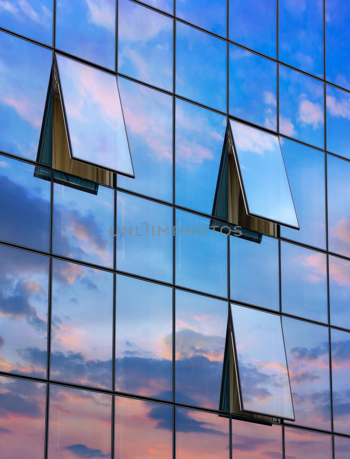 wall glass skyscraper with reflection of the sky and the three open windows at sunset