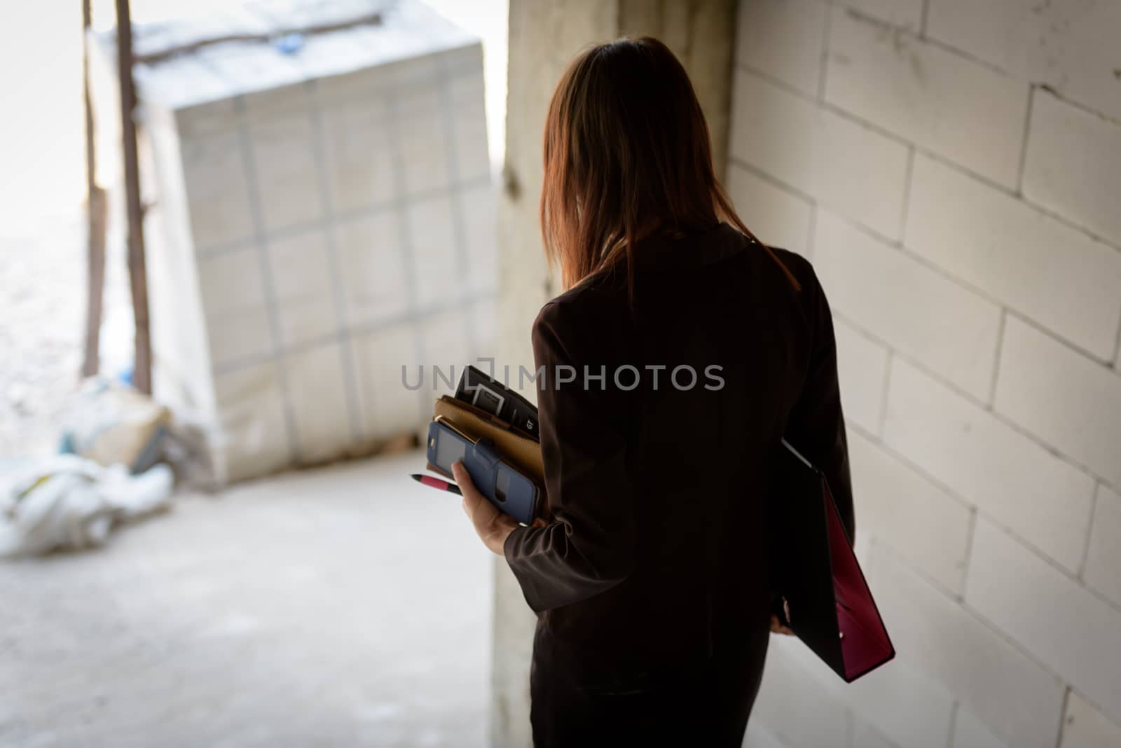 A businesswoman holds a calculator while walking down a stairwell in a building under construction.