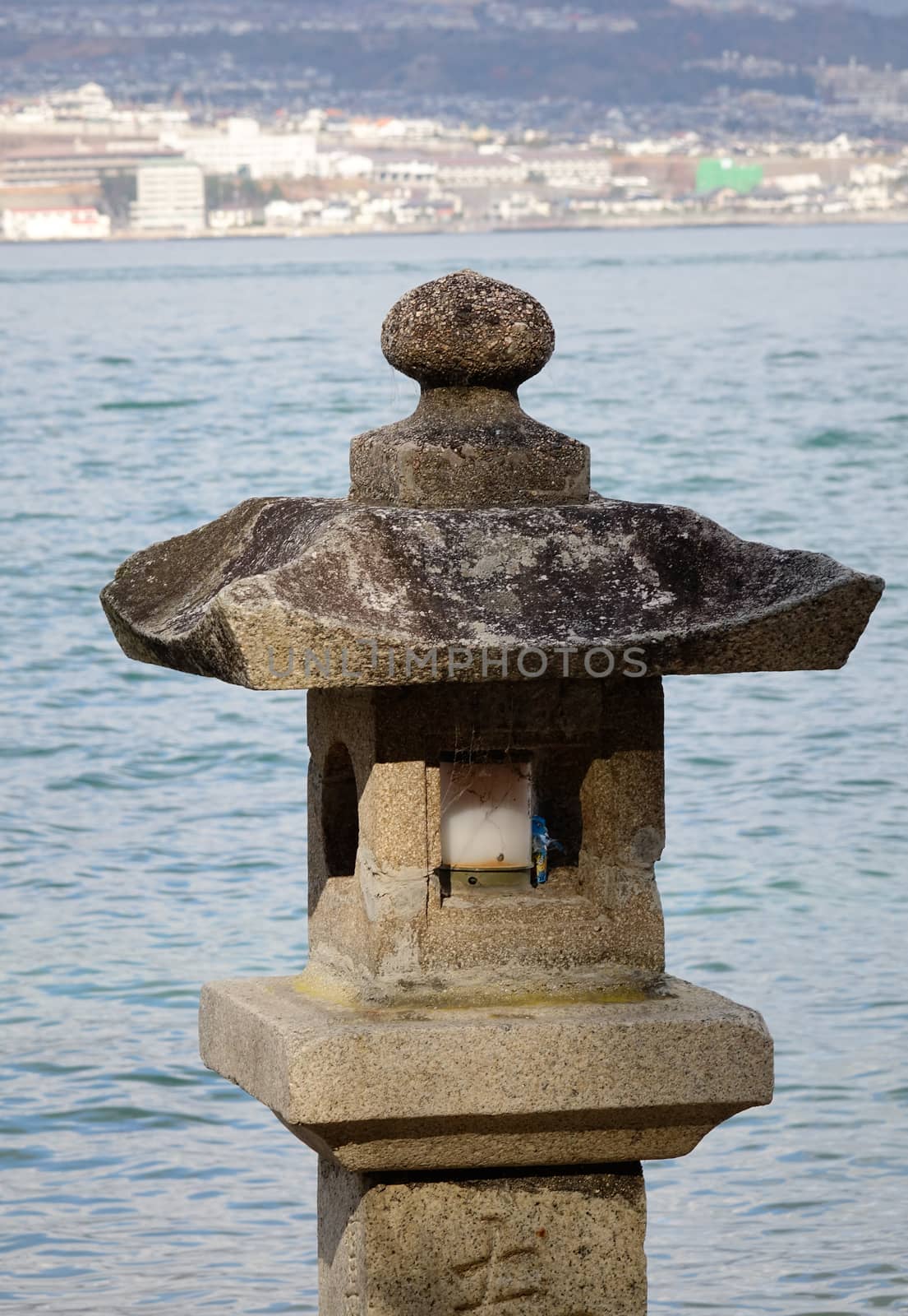 Stone lantern in Japanese garden with seascape background.