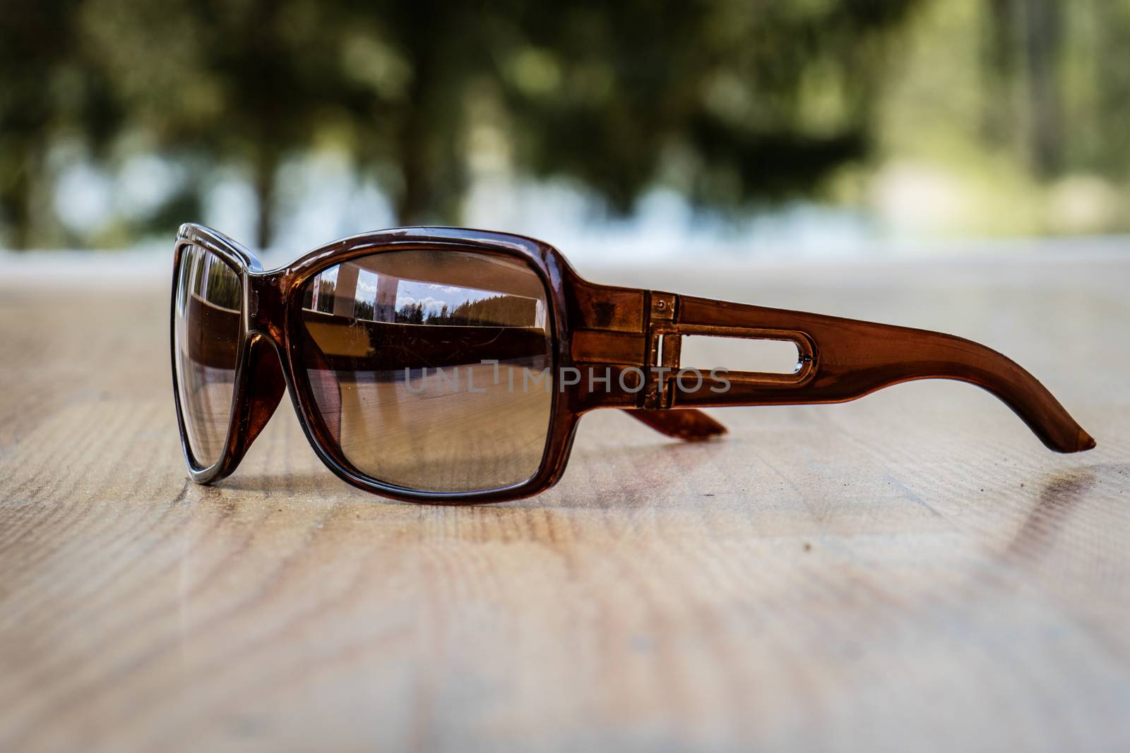 Sunglasses on the table in the sun on a wooden table by wytrazek