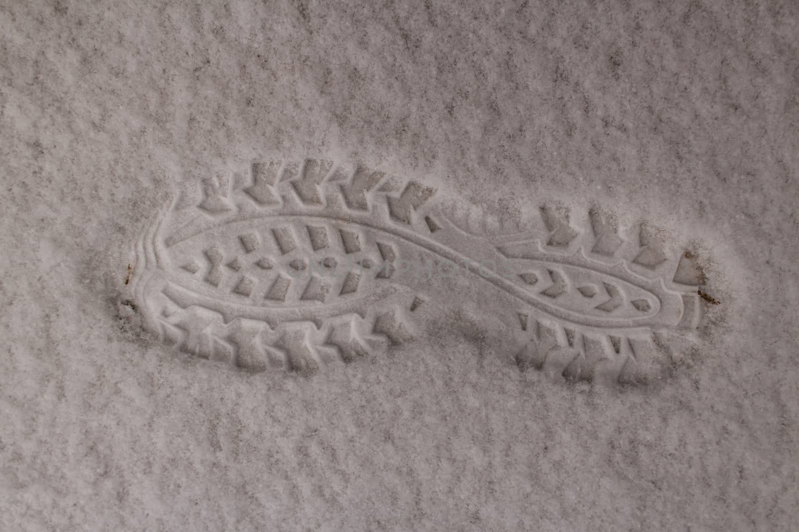 Footprint of the boot on white clear snow. Snow is very fluffy. Winter returned at the end of March.