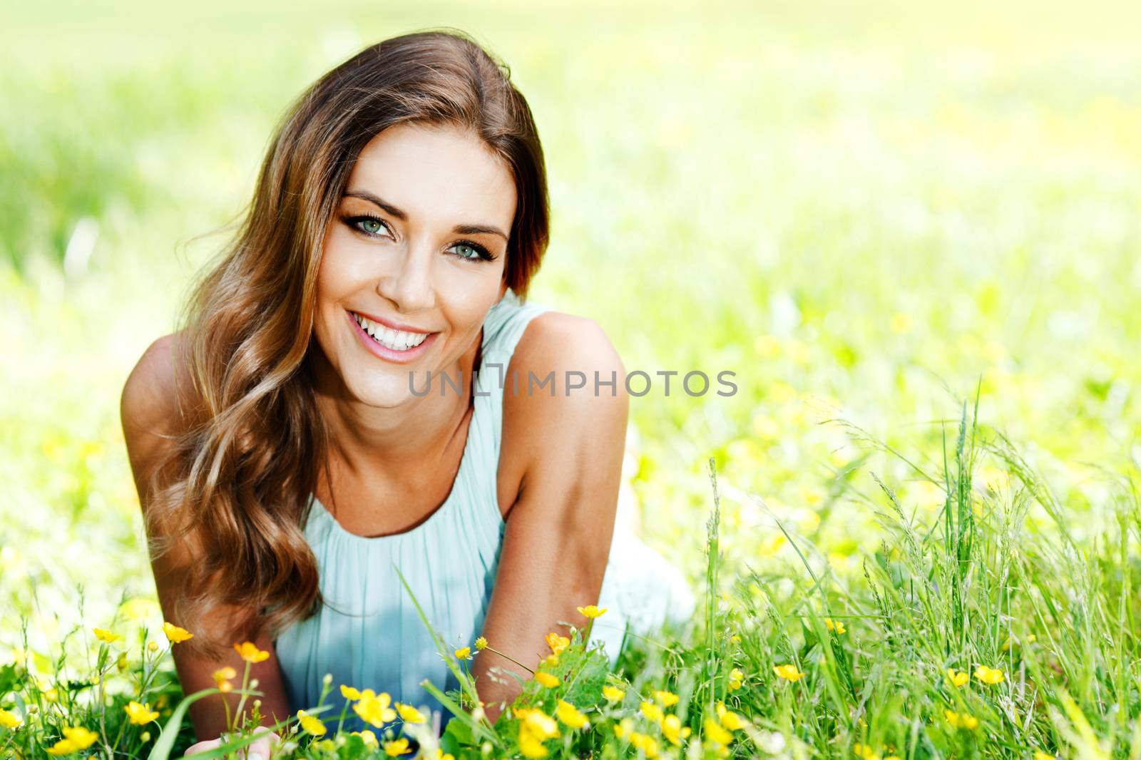Beautiful young woman in blue dress lying on grass