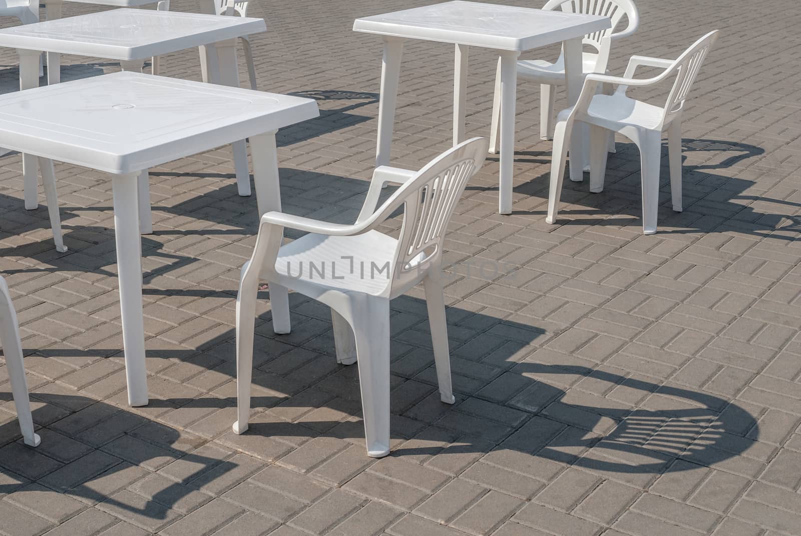 a few plastic chairs and tables on the street, a beautiful sunny day