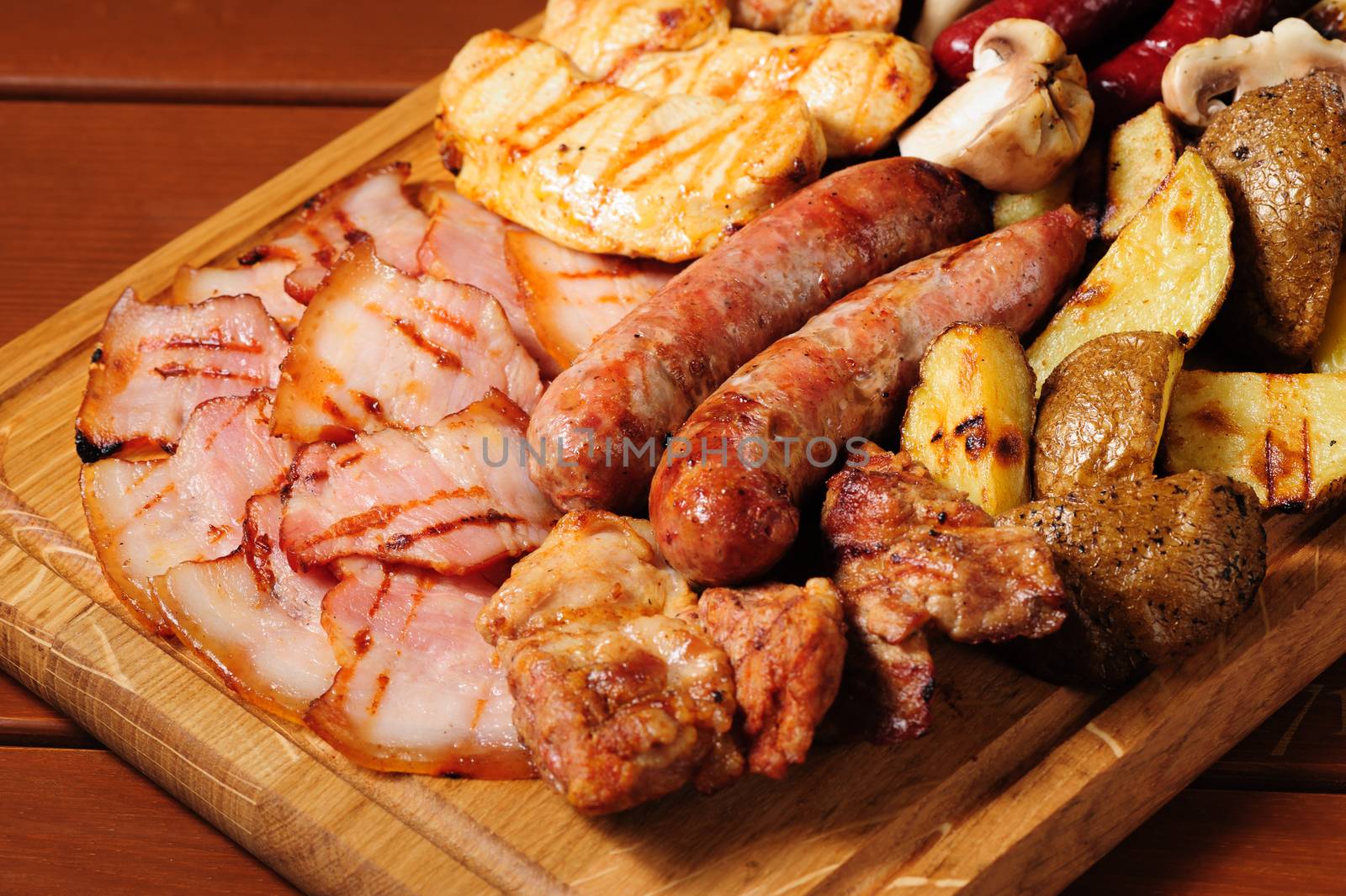 big wooden board with assorted meats, baked potato, preferably served as companion for beer or other alcohol drinks