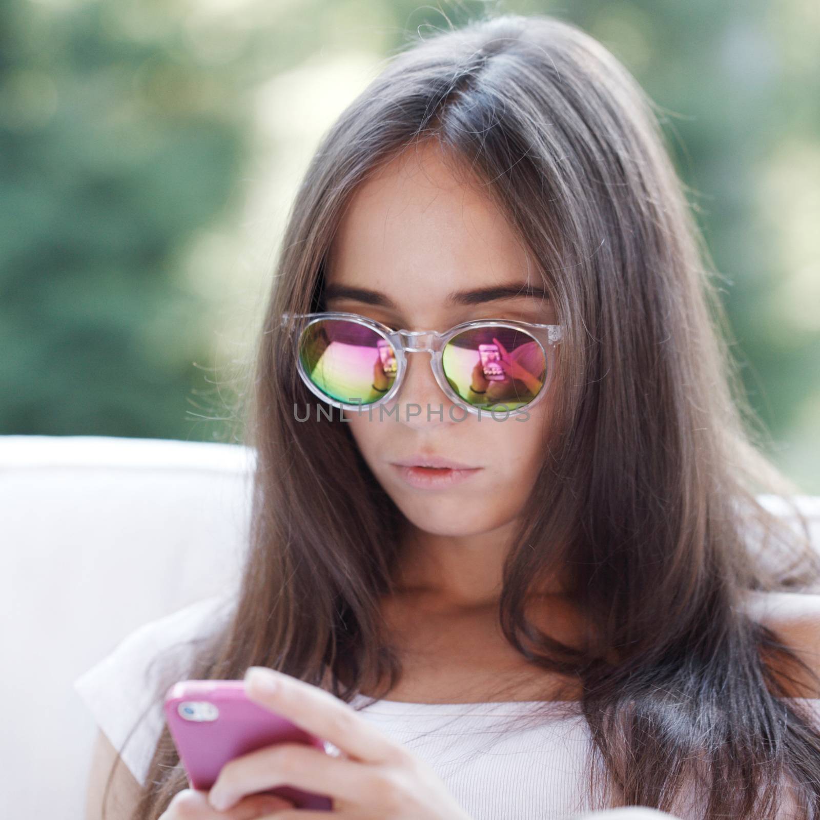 Beautiful young girl with smartphone sitting outdoors