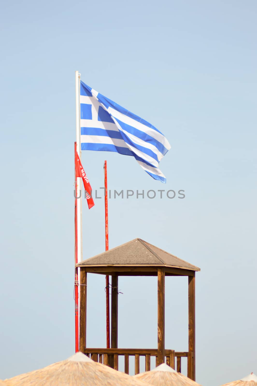 Greek flag floating on a white mat near a guard post on the beach of Amoudara on the island of Crete