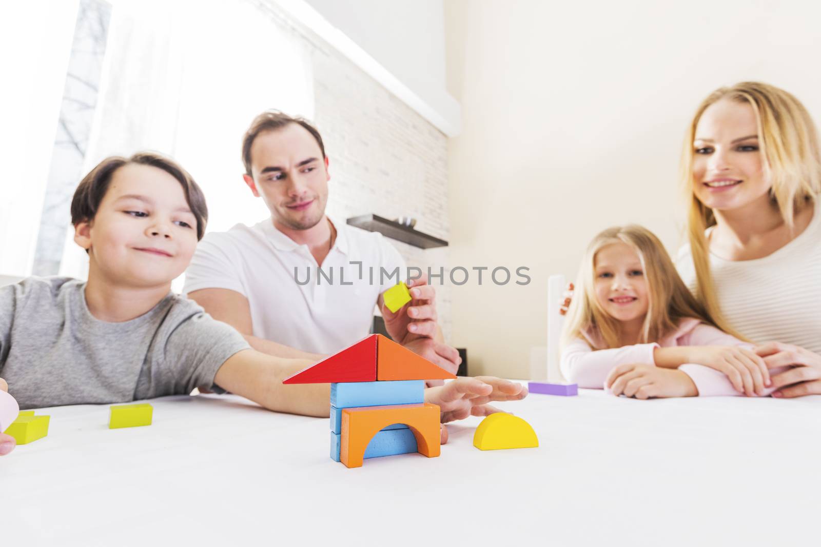 Family of four people with children constructing house of toy blocks, real estate concept
