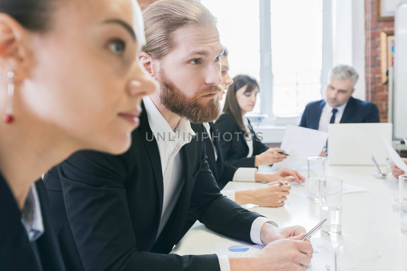 Business people sitting at the table in a row and work with documents