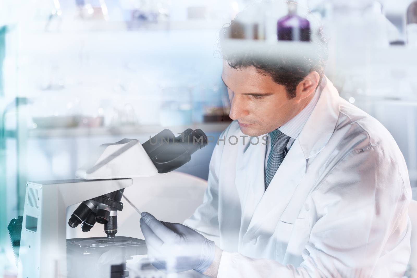 Life scientist researching in laboratory. Attractive young male scientist looking at the microscope slides in laboratory. Healthcare and biotechnology concept.