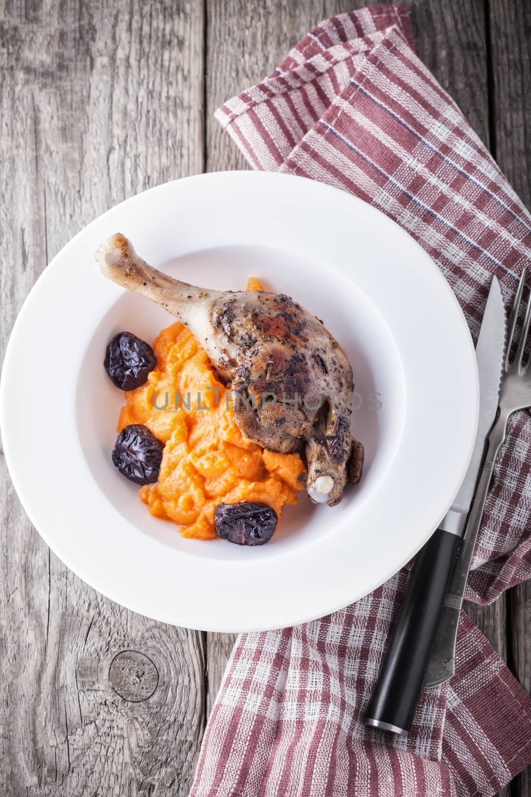 Roasted duck leg with mashed carrot and dried prunes.