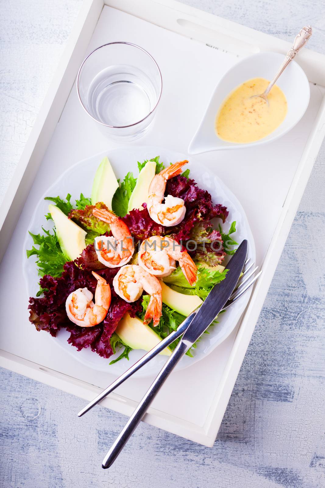 Avocado shrimp salad with mustard sauce on a tray.