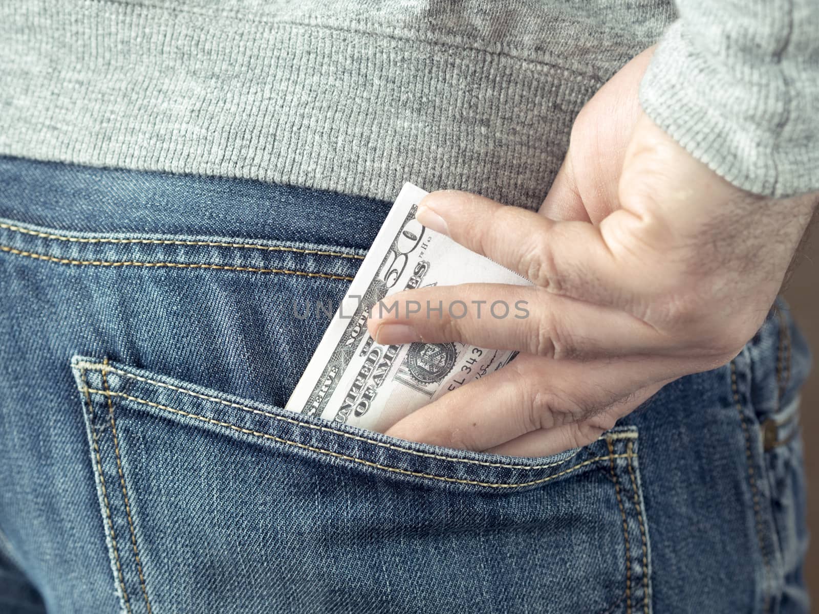 his hand put dollars in jeans pocket or take out from pocket