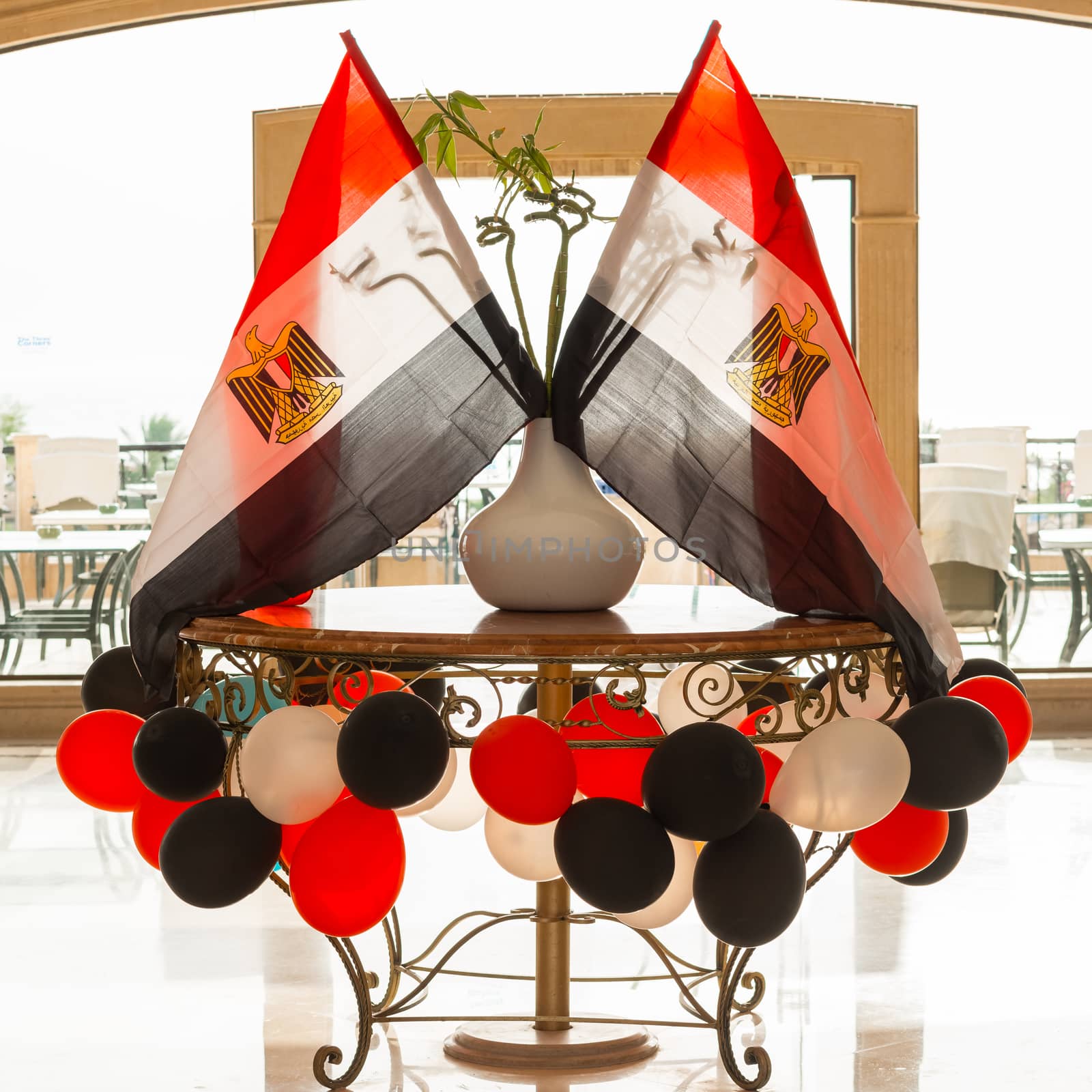 Egyptian flags in backlight, around colored balloons, in a hotel lobby