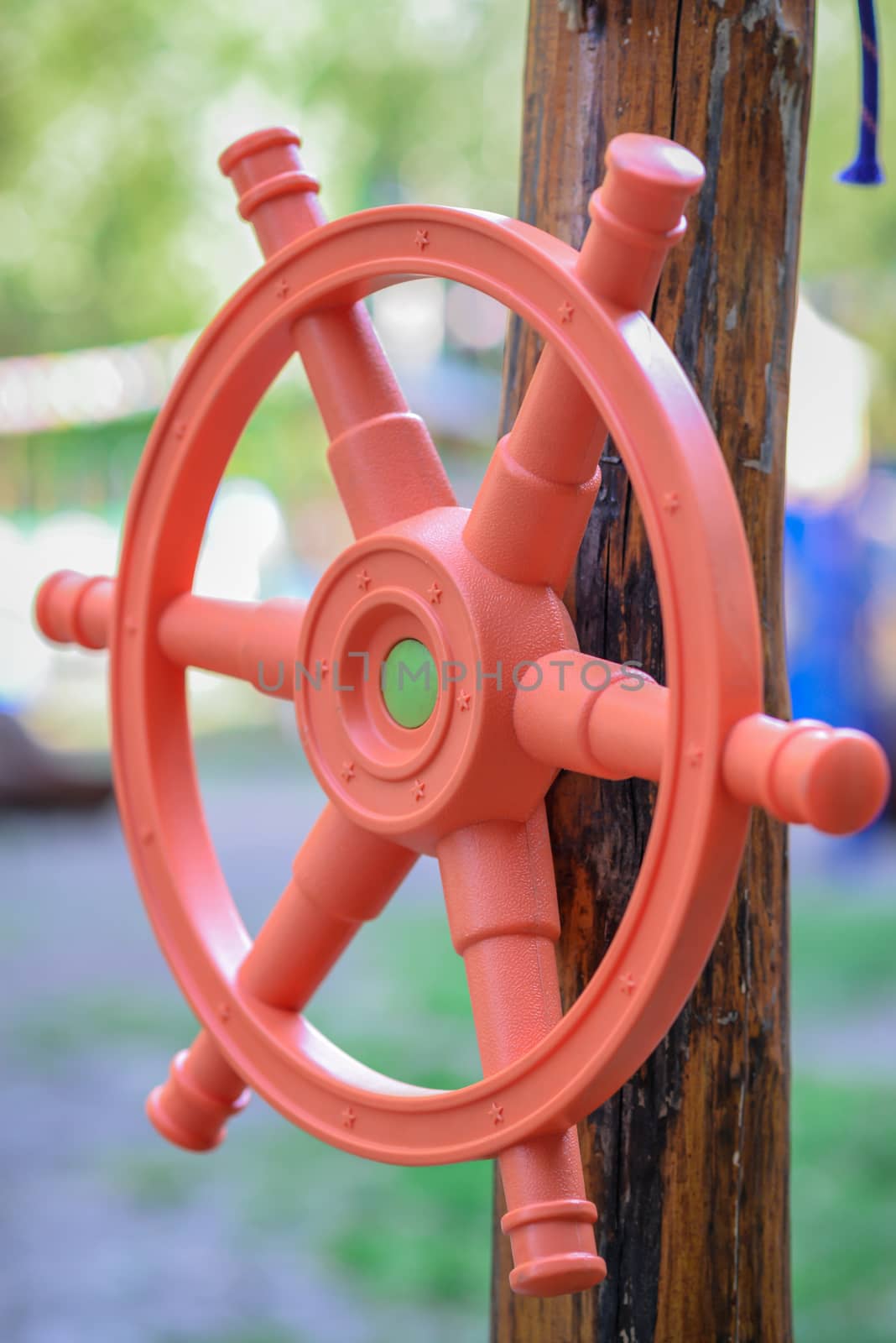 Red plastic children's handlebar of the ship a wooden girder on the playground