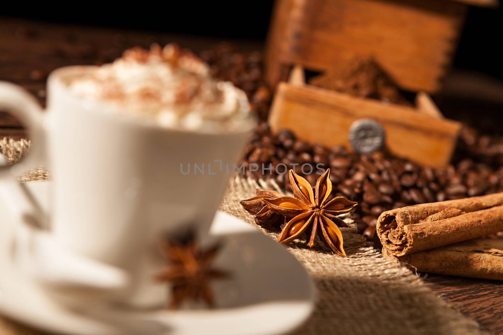 Close-up on star anise and cinnamon sticks with coffee cup and whipped cream