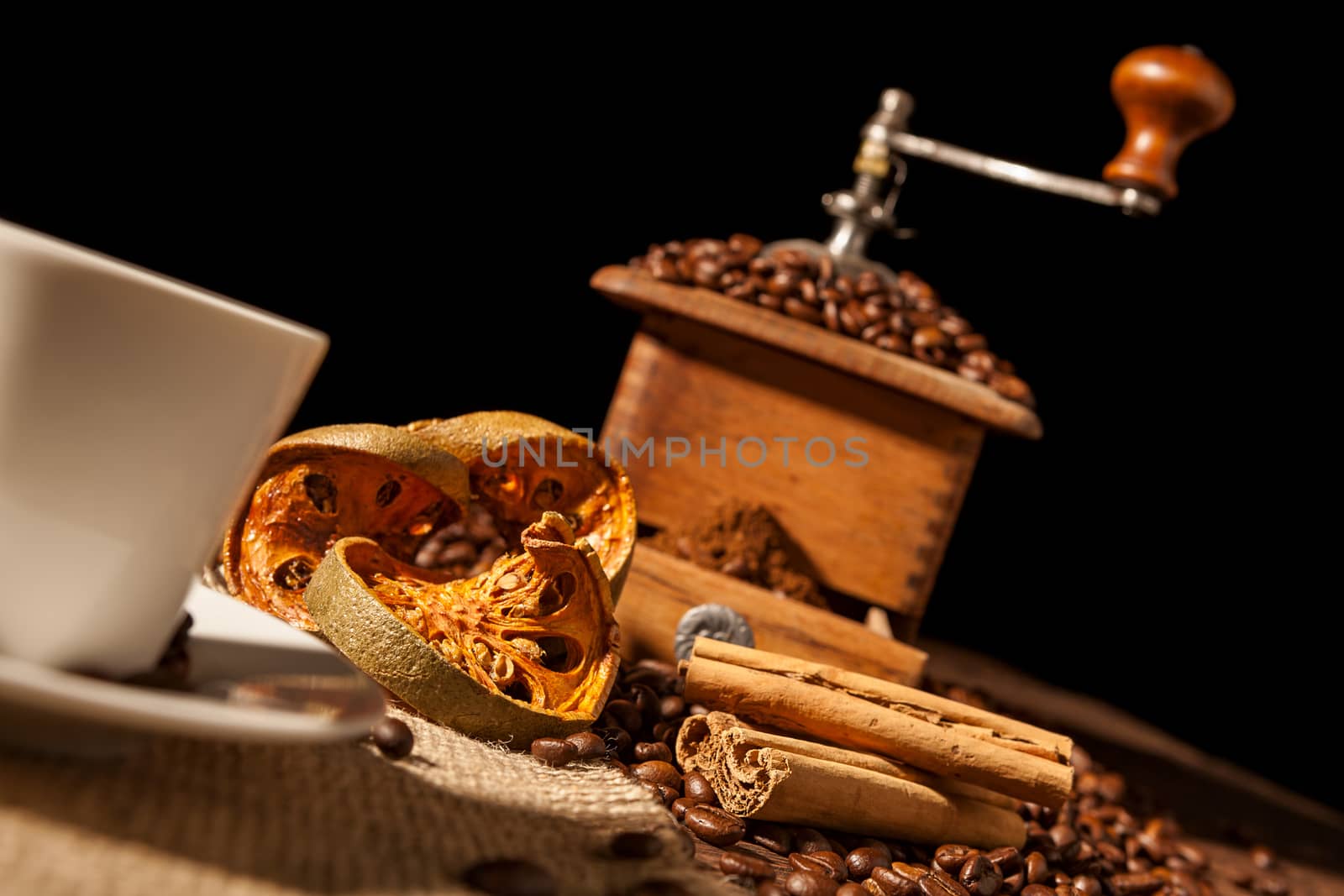 Close-up on dried orange fruit and cinnamon sticks with coffee grinder and black background
