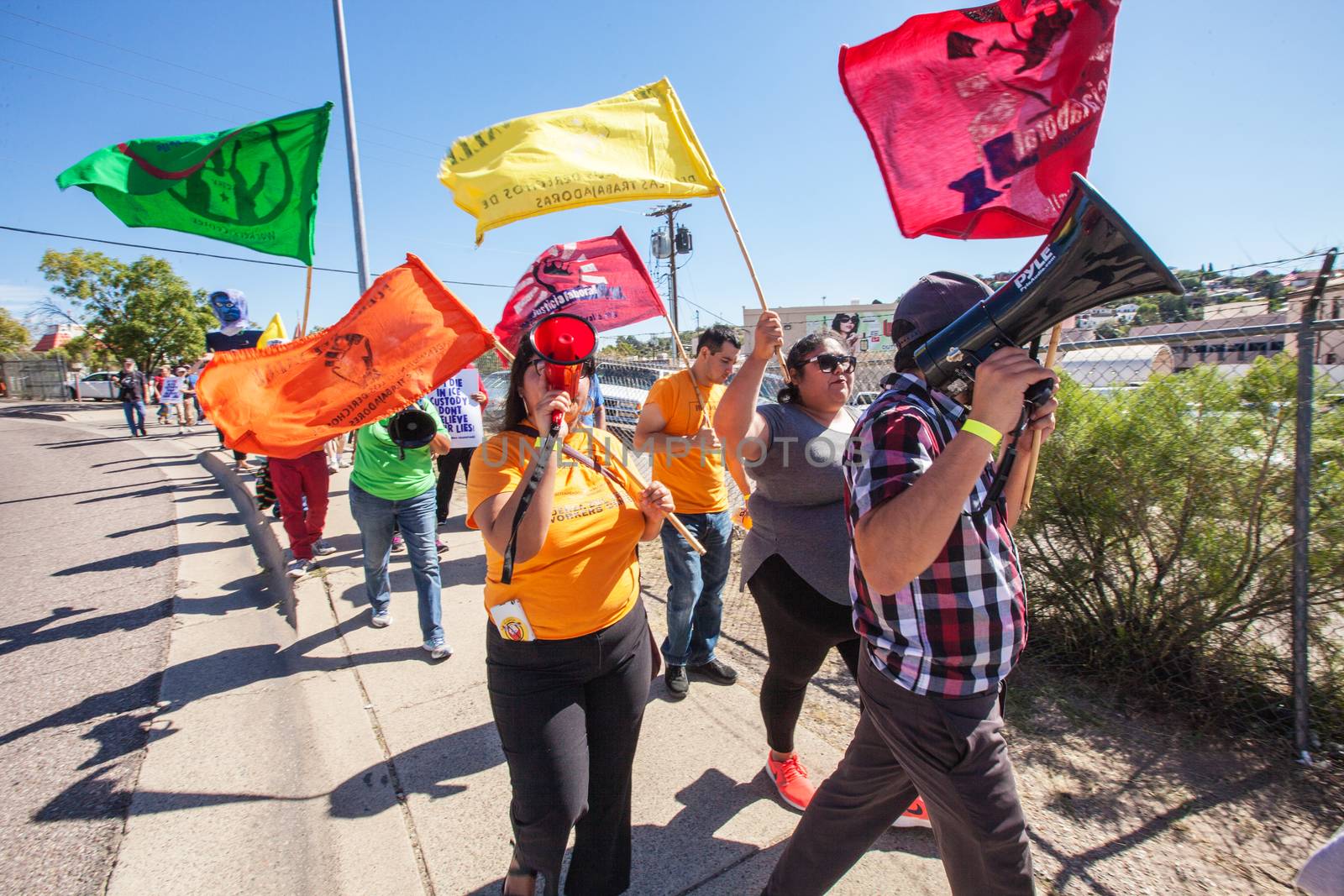 Marchers with colorful flags at border protest by Creatista