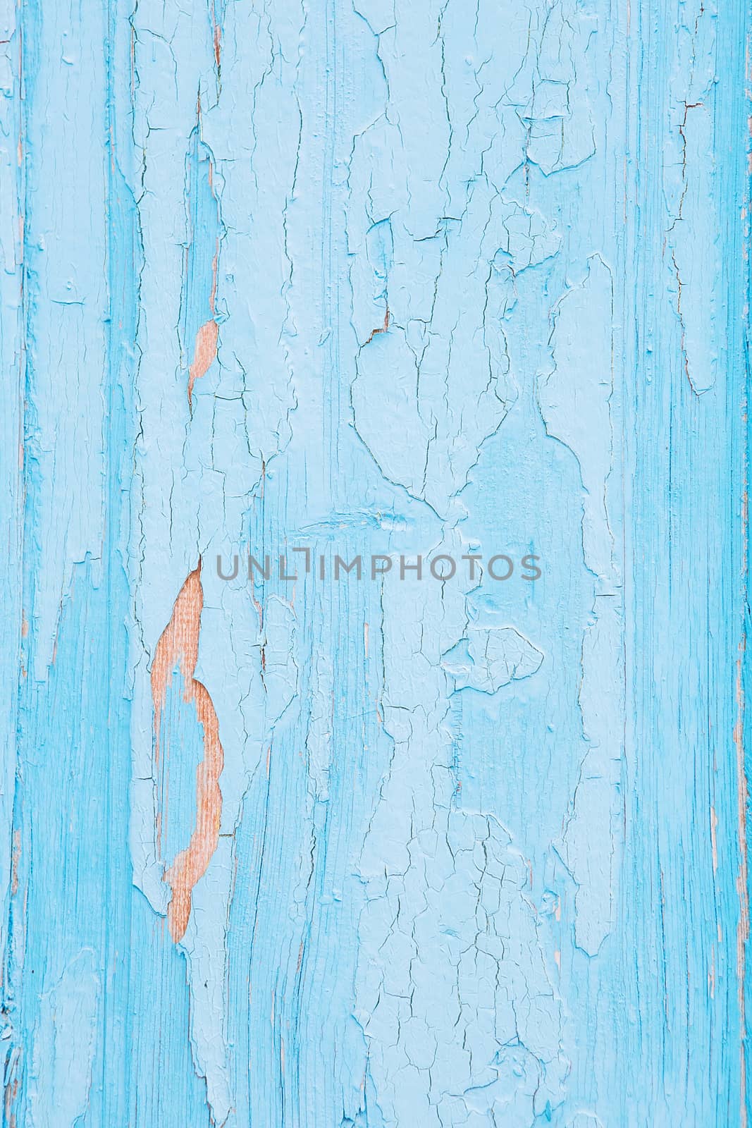 Cracking and peeling blue paint on a wall. Vintage wood background with peeling paint. Old board with Irradiated paint