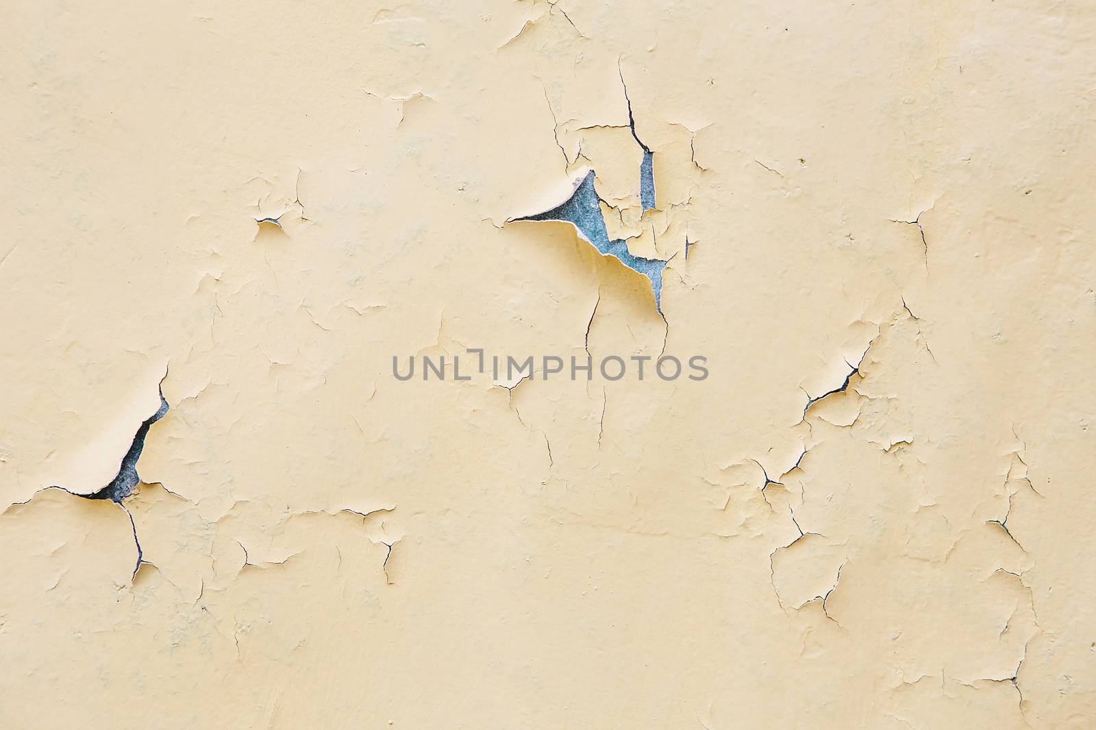 Cracking and peeling yellow paint on a wall. Vintage wood background with peeling paint. Old board with Irradiated paint
