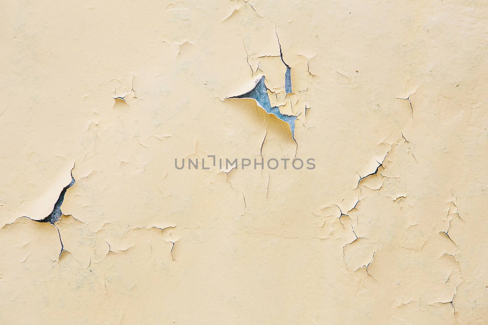 Cracking and peeling yellow paint on a wall. Vintage wood background with peeling paint. Old board with Irradiated paint