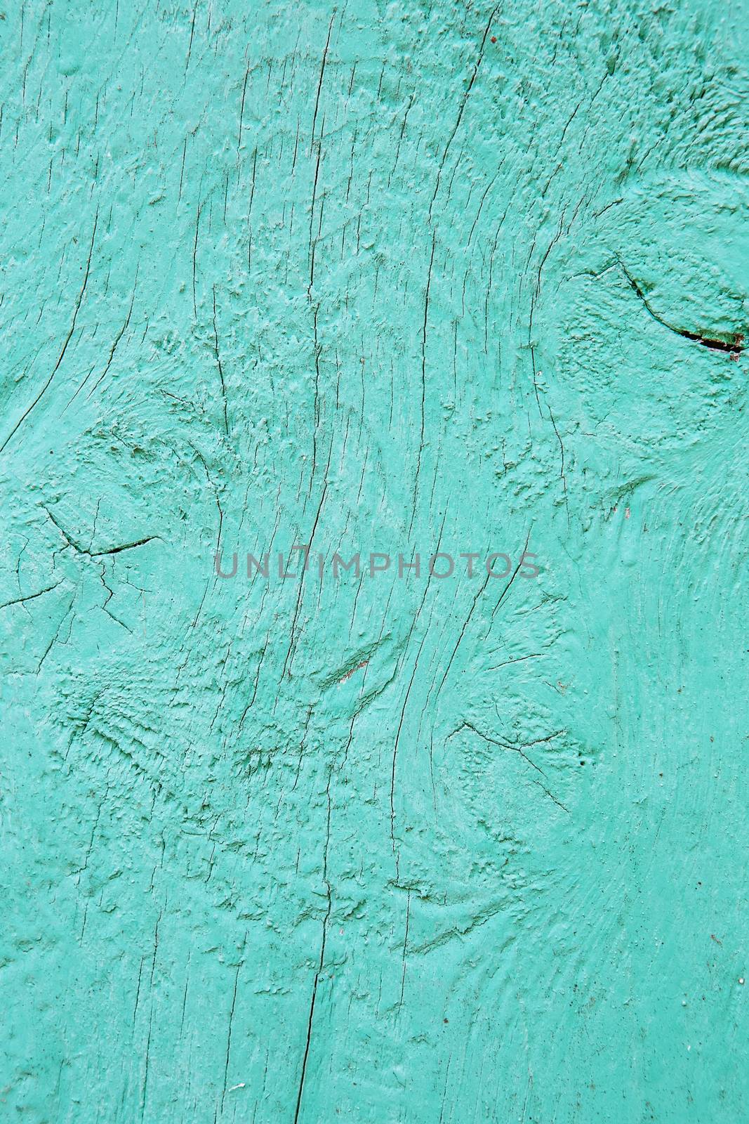Cracking and peeling turquoise paint on a wall. Vintage wood background with peeling blue paint. Old board with Irradiated paint