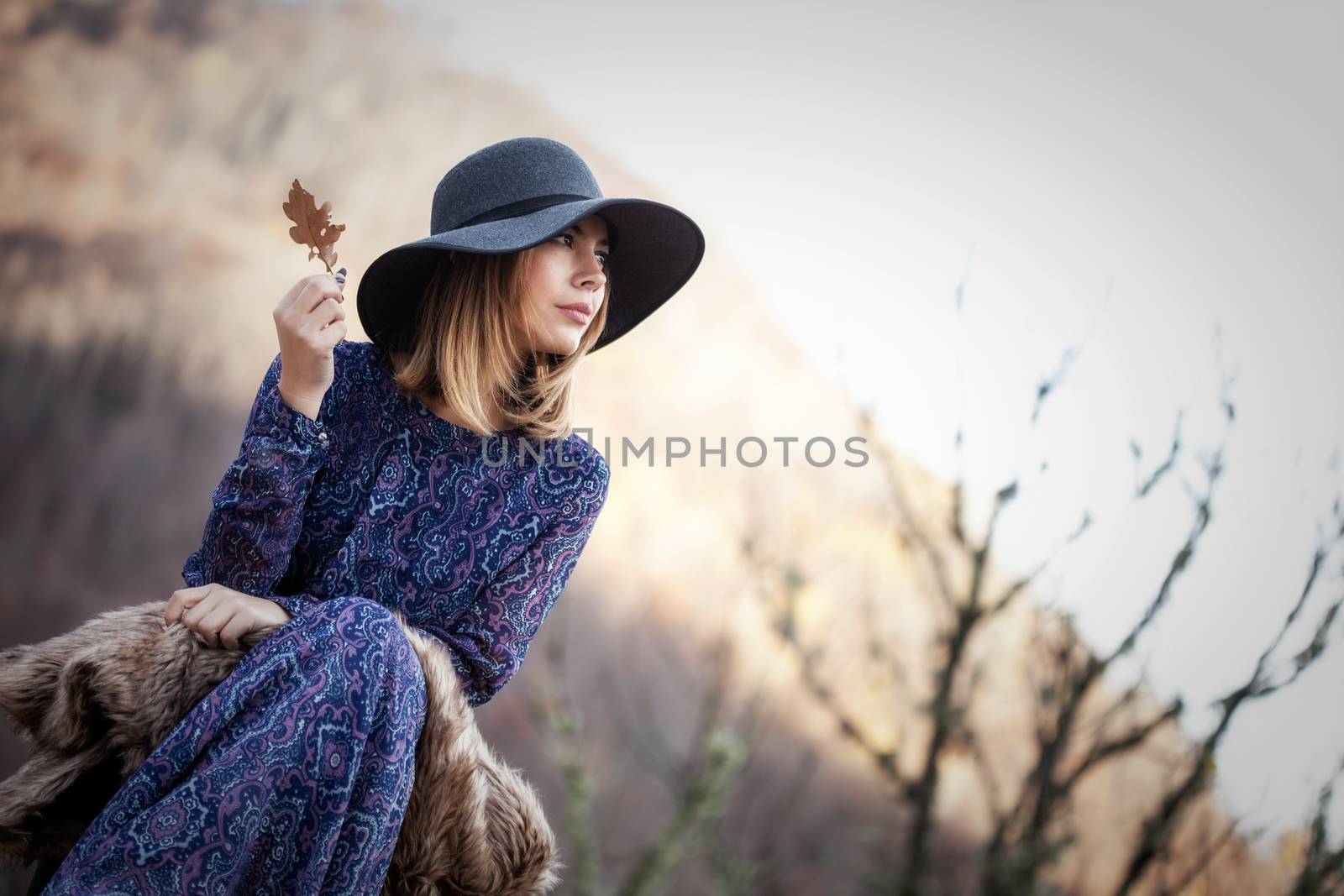 pretty young woman holding a leaf in nature, vintage style outfit