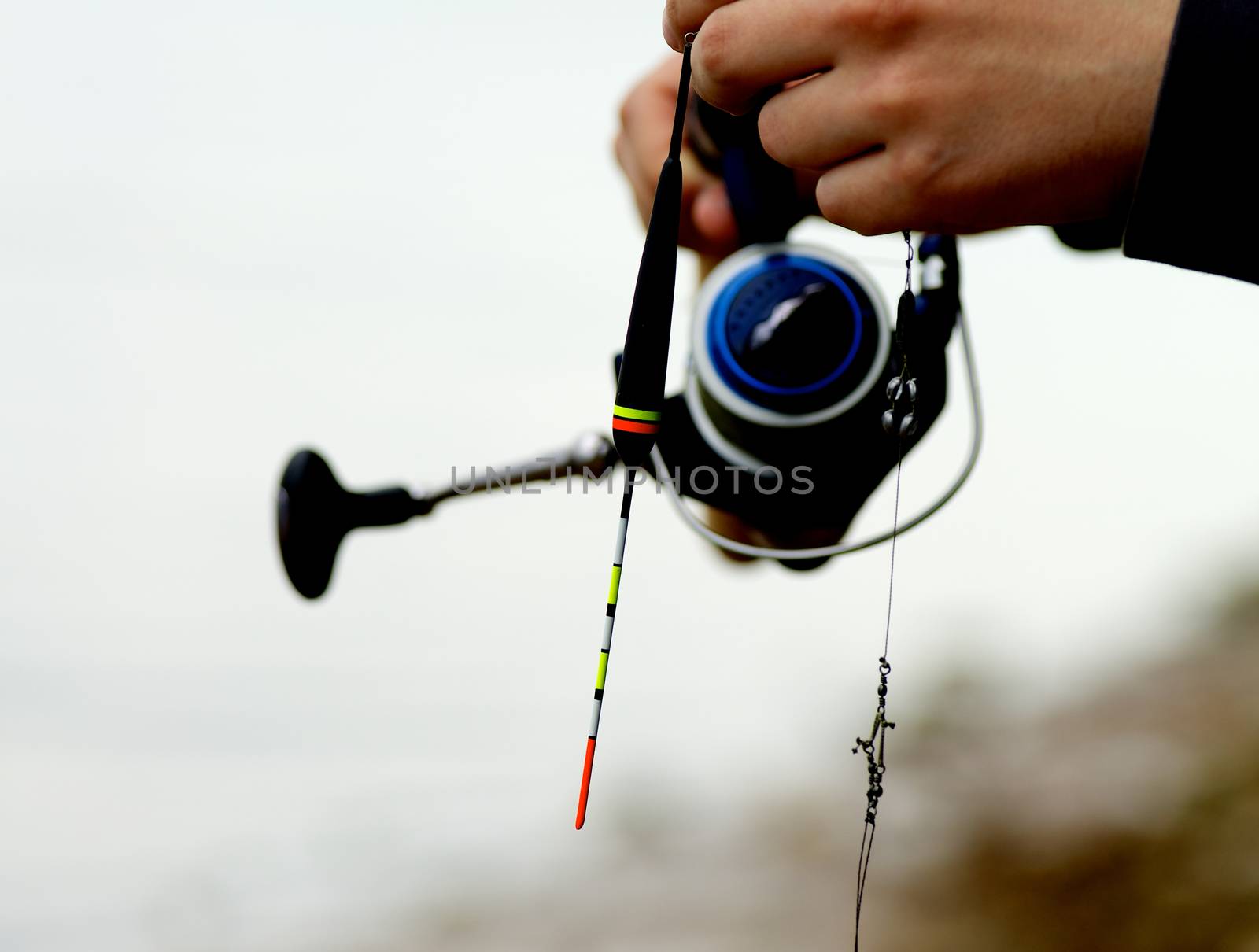 Man Holding Fishing Rod on Blurred Nature background Outdoors. Focus on Bobber   