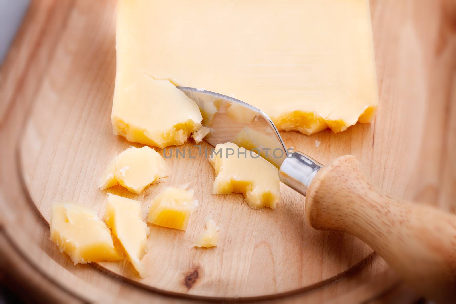 Parmesan cheese and knife on a wooden chopping board, selective focus
