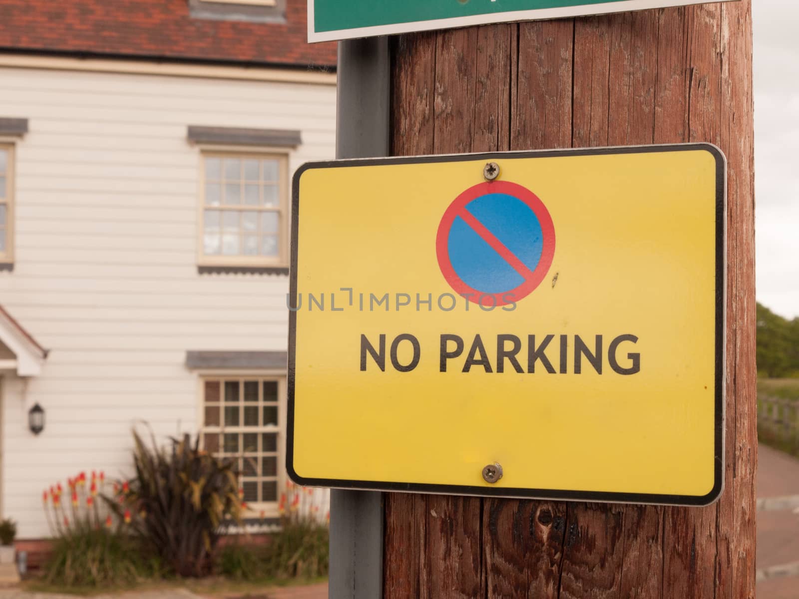 a yellow warning traffic sign outside saying no parking allowed on wood pole