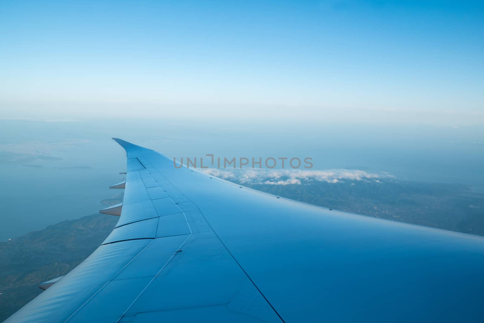 wing of an airplane flying above city and sea