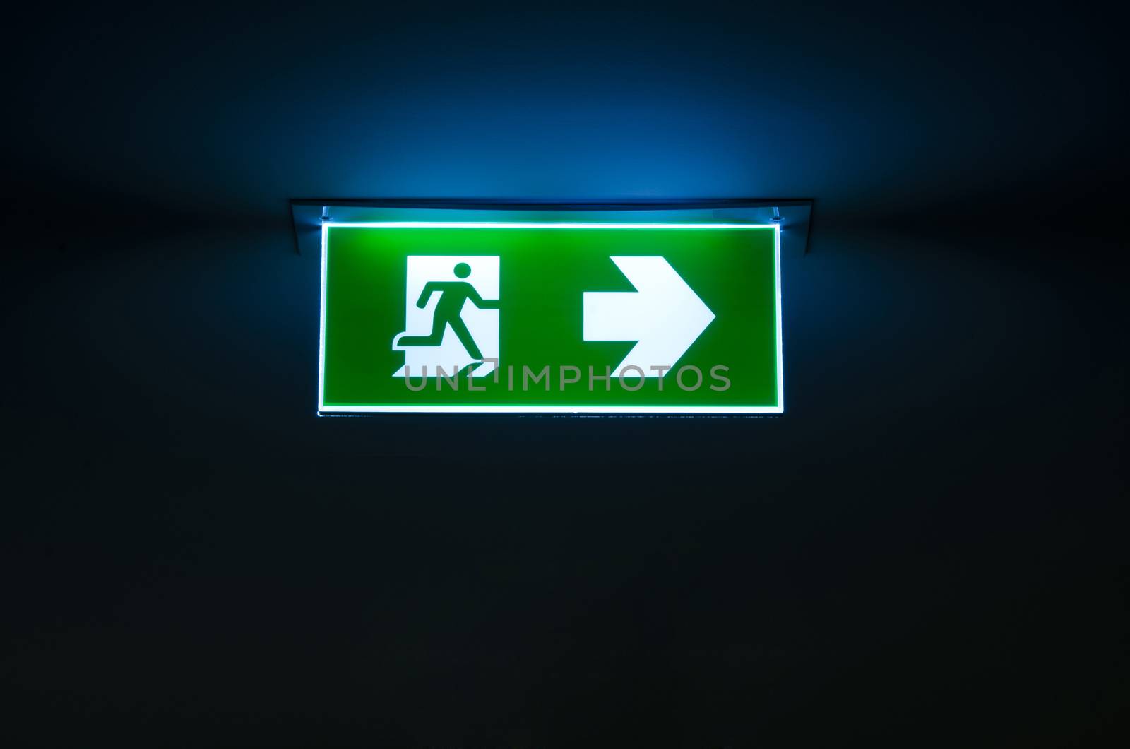 green emergency exit sign showing the way to escape