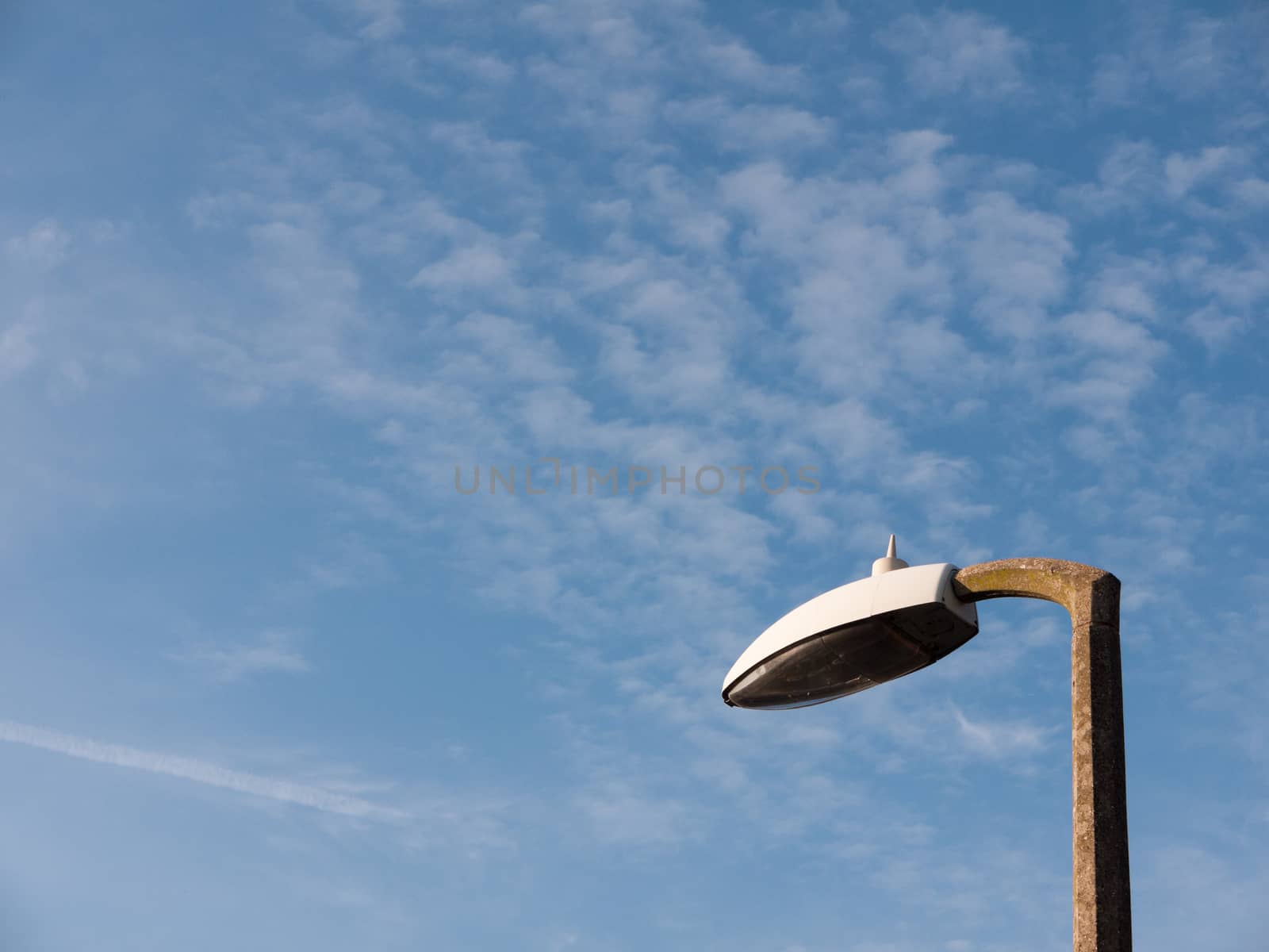 the top of a street light outside turned off during day with a blue and white sky broken not working and turned off spring day