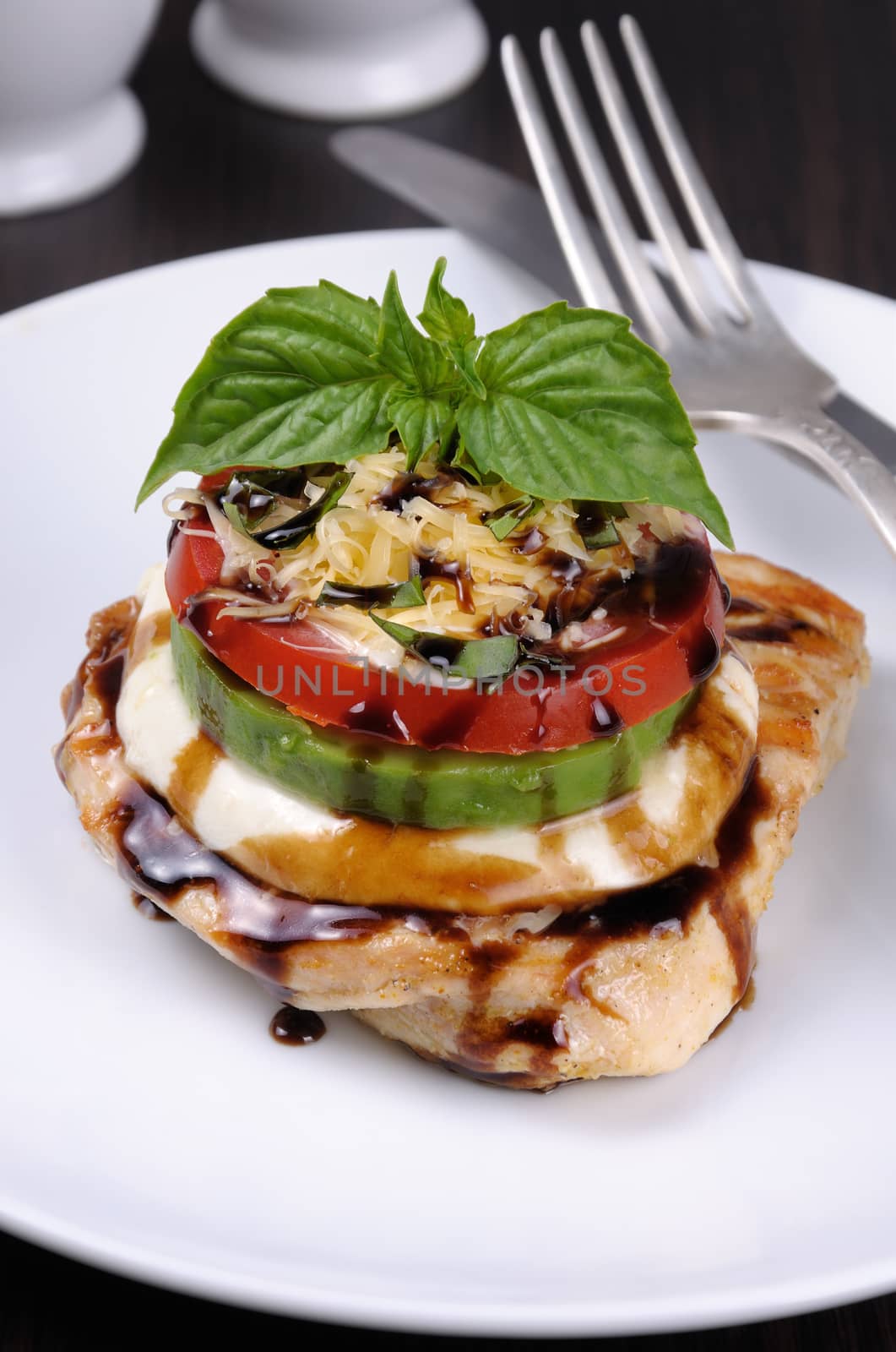 Chicken breast with slices of mozzarella, avocado, tomato and basil