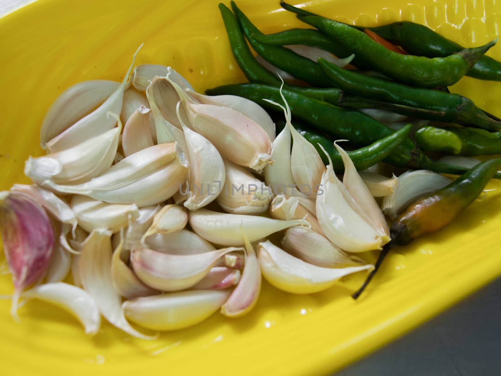 COLOR PHOTO OF CLOSE-UP SHOT OF RAW GARLIC AND GREEN CHILLI PEPPERS ON PLATE