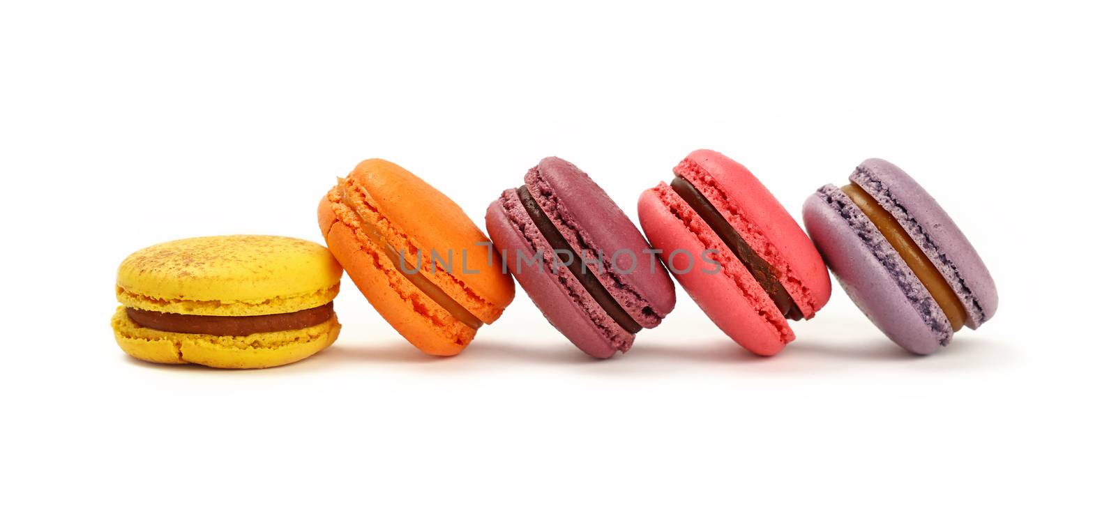 Row of several fresh colorful traditional French macaroon pastry cookies (macarons, macaroni) isolated on white background, close up, low angle view