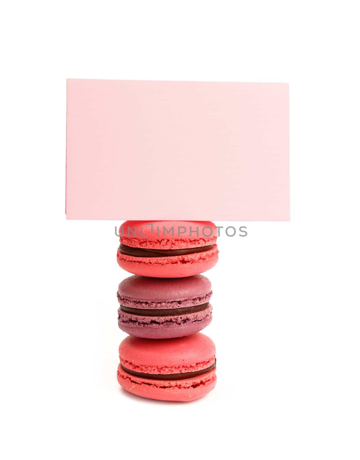 Stack of colorful traditional French macaroon pastry cookies (macarons, macaroni) with pink paper sign isolated on white background, close up, low angle view