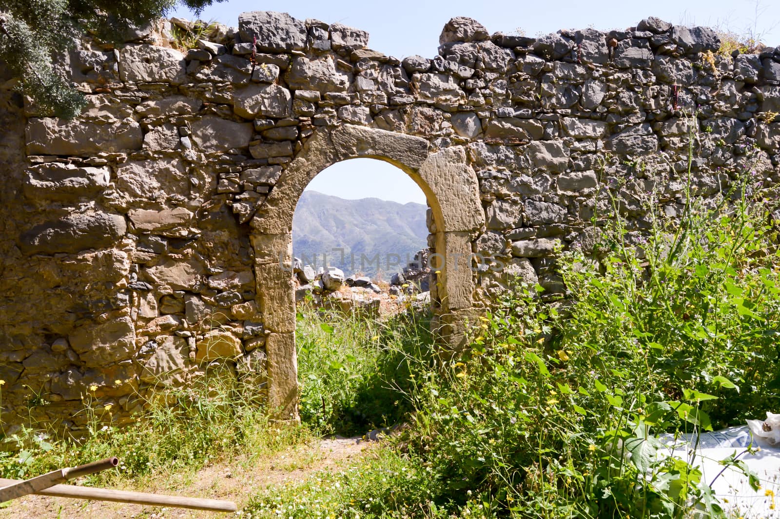 Ruined wall with an arcade door and a view of the Crete mountains