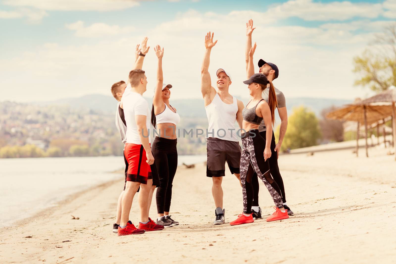 Group happiness young friends having a sports greeting before workout on the beach.