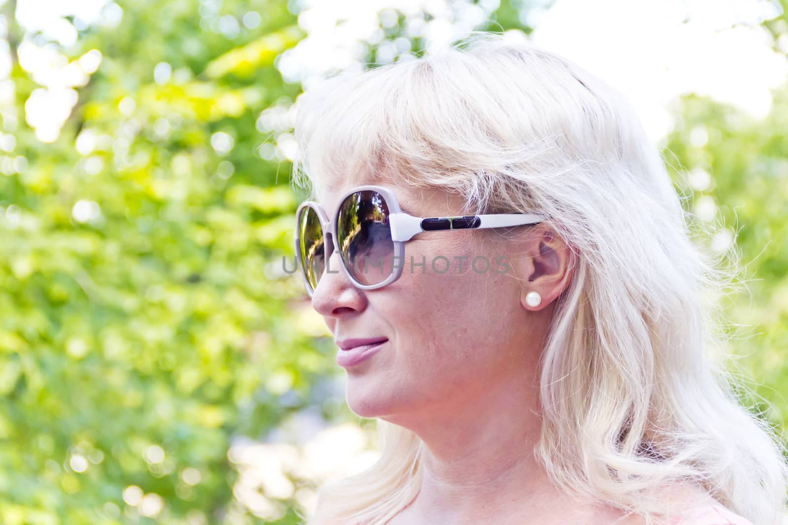 Blond woman in sunglass on green background